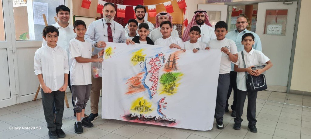 طلاب وكبار يعرضون لافتة جماعية بعنوان بصمة في حب الوطن وخريطة البحرين ورموز وطنية داخل المدرسة
