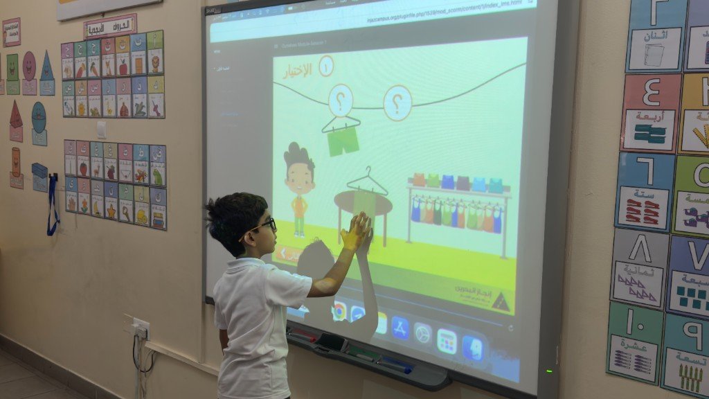 طالب يتفاعل مع السبورة الذكية ضمن نشاط تعليمي رقمي عن الاختيار والتواصل