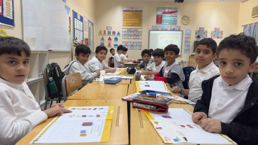 طلاب يعملون معًا على طاولات مدمجة في بيئة صفية تعزّز التعاون والمشاركة