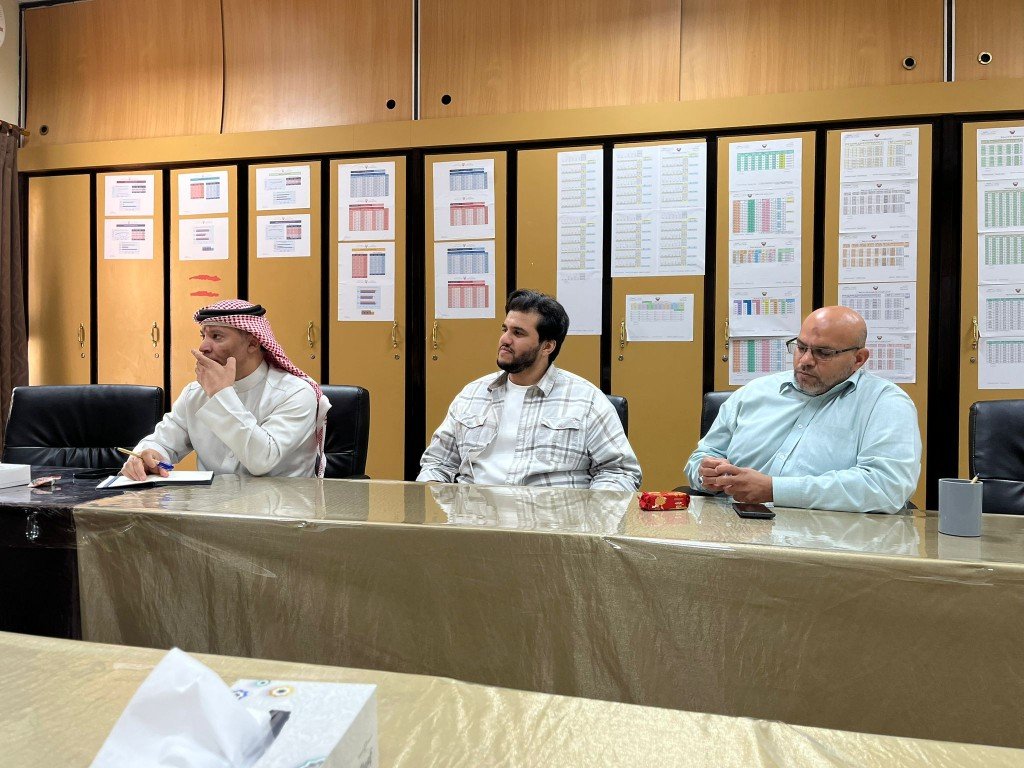 توثيق اجتماع قسم نظام الفصل — مناقشة ومتابعة أمام جداول معلّقة على الخزائن