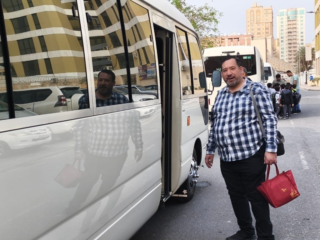 أ. فاضل يحيى بجانب حافلة مدرسية خلال تنظيم رحلة أو نشاط ميداني