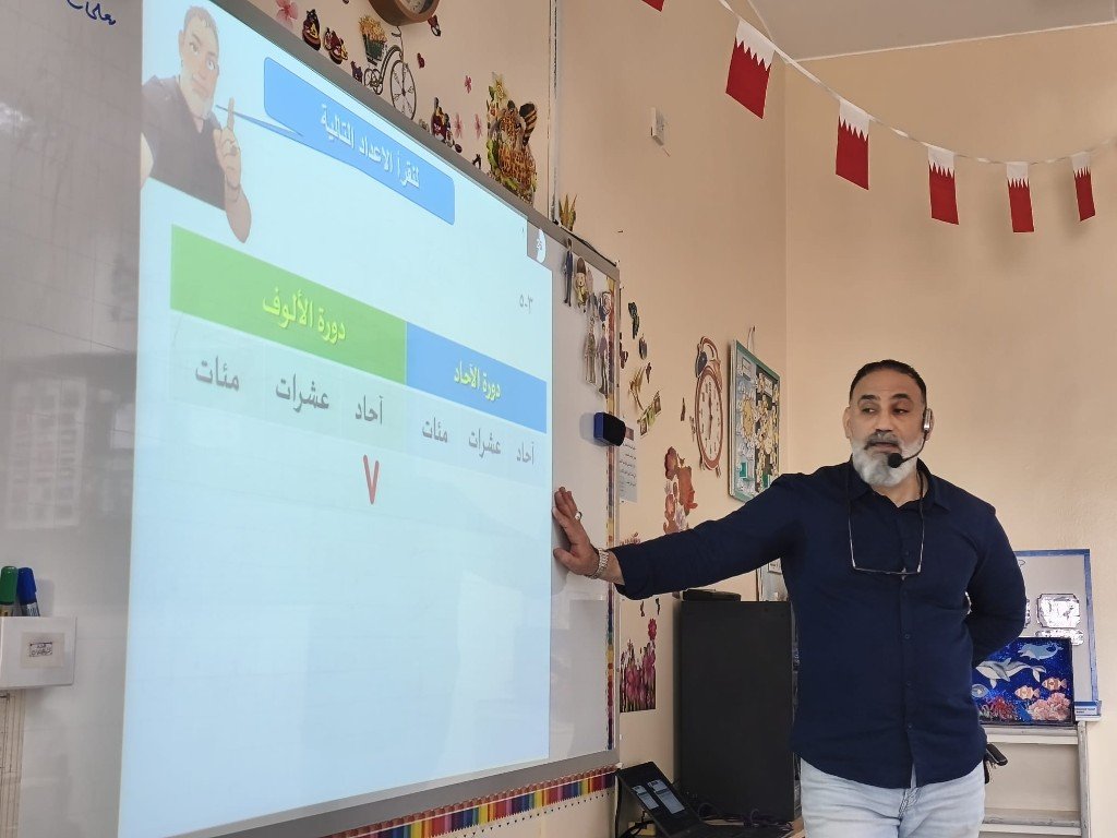 أ. منير صالح أثناء شرح الرياضيات على السبورة التفاعلية — درس الأعداد والدورات