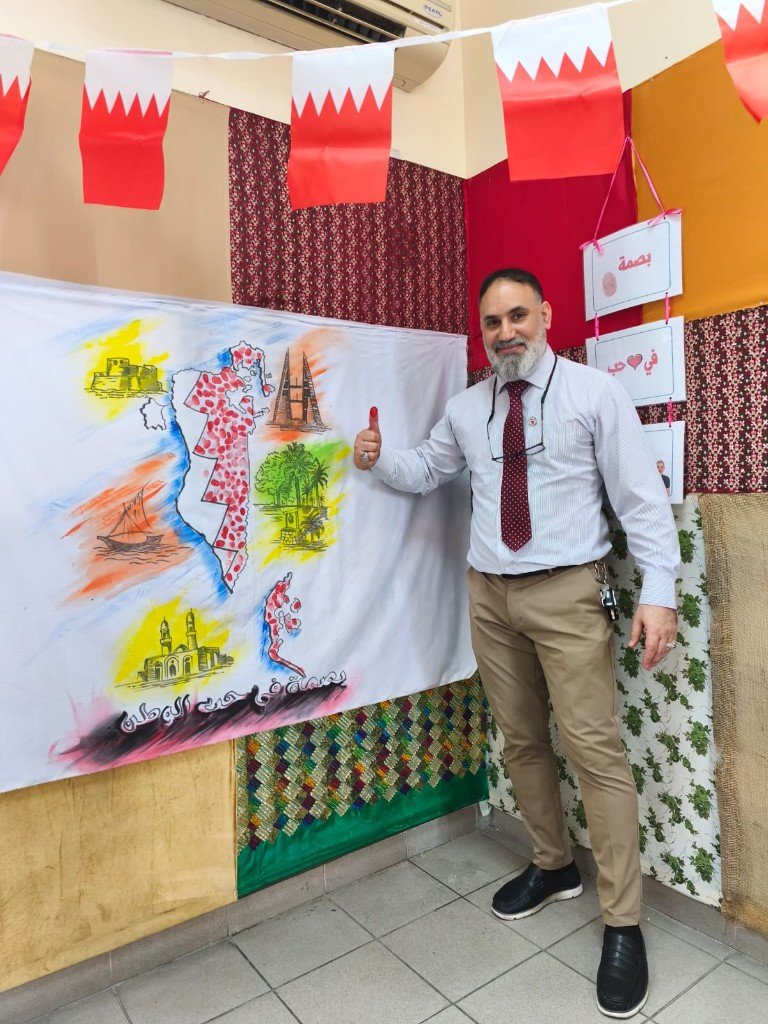 أ. منير صالح بجانب لافتة فعالية بصمة في حب الوطن وخريطة البحرين